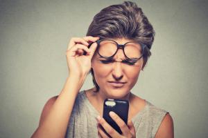 A woman reading a phone with glasses.