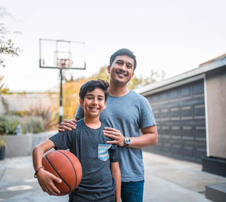 A father and son holding a basketball together.