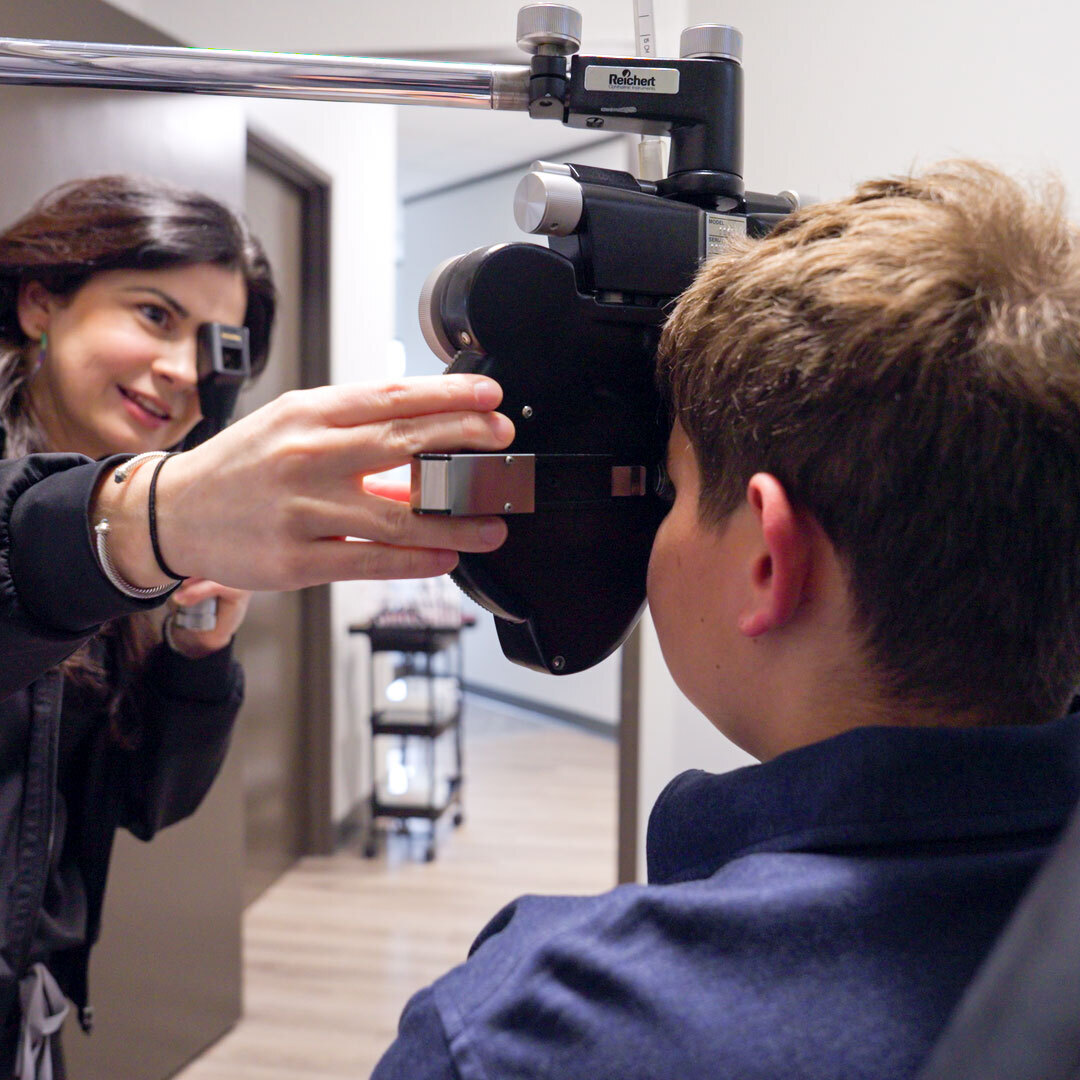 A female doctor performing an eye exam on a young boy.