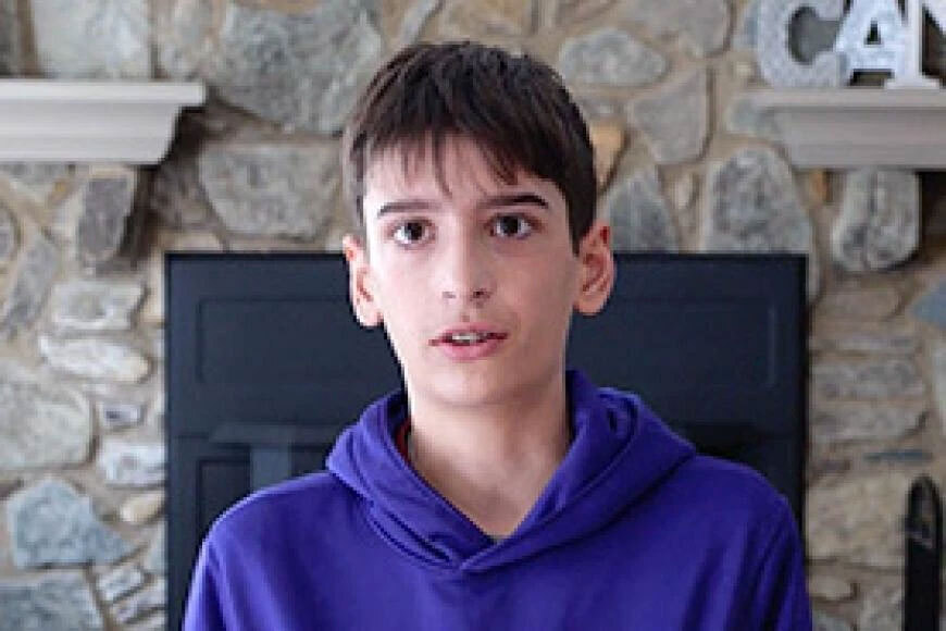 Photograph of a boy in front of his family's fireplace.