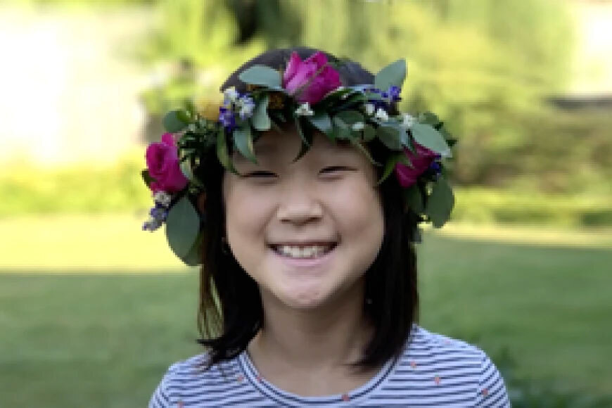 Photograph of a girl smiling outside while wearing a flower crown.