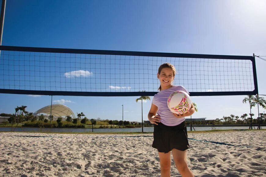 Photograph of a girl posing with a volleyball on the beach.