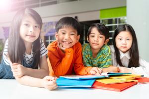 Cheerful Asian children reading book.