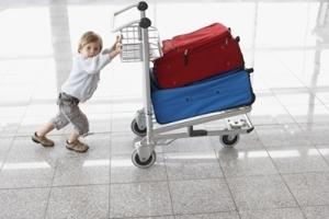 A toddler pushing a cart of luggage.