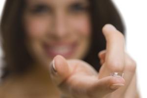 A woman holding a contact lens.
