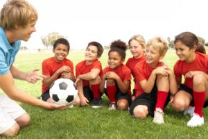 A children&#039;s soccer team smiling at their coach.