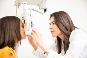A young optometric associate providing an eye exam and myopia management services for a school-aged girl.