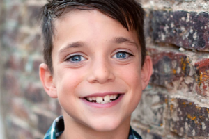 boy smiling by a brick wall