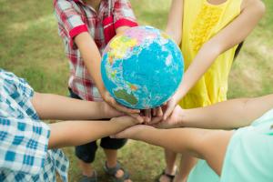 A group of young children standing in a circle holding a globe