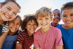 A happy group of elementary-school-aged children smiling and outside.