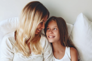 mom and girl smiling at each other with pillows behind them