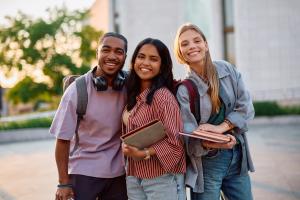 three smiling college students on the campus quad