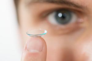 close-up of woman holding contact lens on her finger