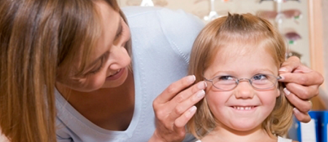 young girl trying on glasses at eye examination