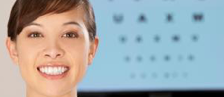 woman smiling next to eye chart