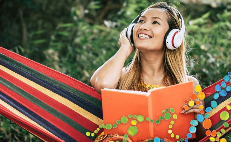 woman smiling with headphones and holding a book