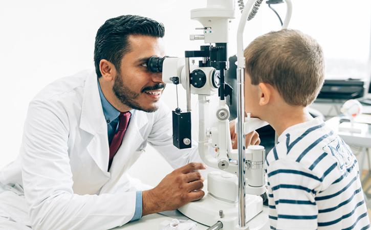 Optometrist examining pediatric patient&#039;s eye.