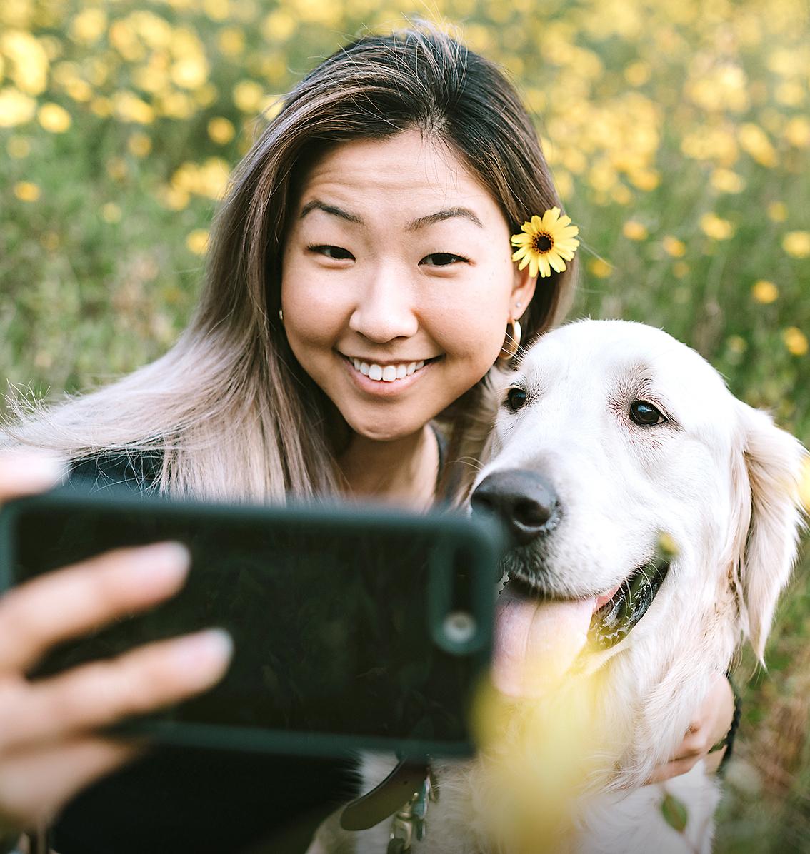 woman taking a photo with a golden retriever