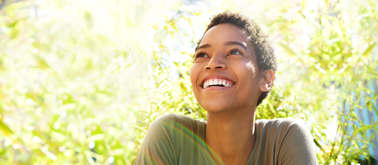 Woman outdoors looking up and smiling