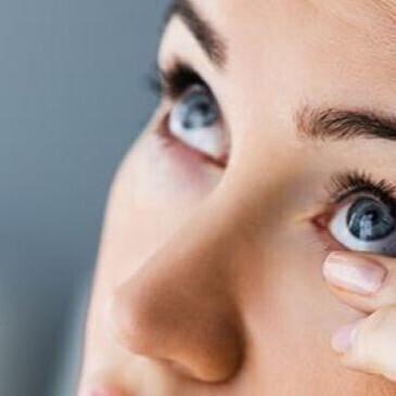 woman adjusting contact lenses in her eye