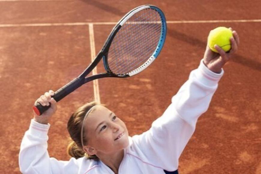 girl serving tennis ball
