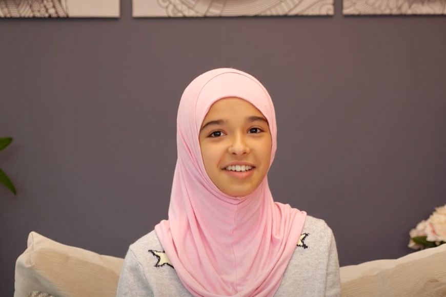 girl wearing hijab, sitting on a couch, and smiling