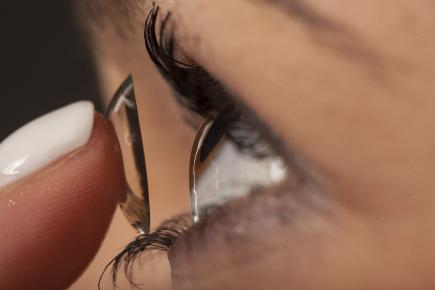 woman applying contact lens.