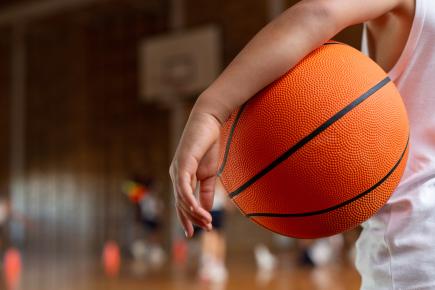 young boy holding a basketball on a basketball court