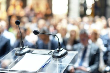 A full lecture hall with a closeup of a podium with microphones