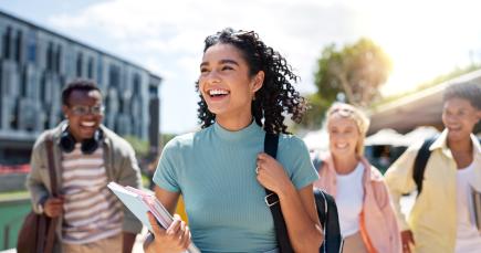 a happy female college student walking to class