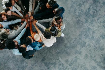 a group of people in a circle holding their hands together to symbolize teamwork and support