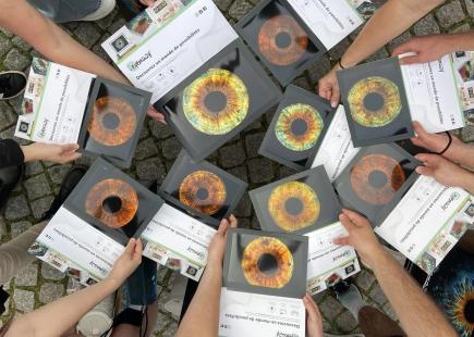 optometry students in a circle holding pictures of a closeup of an eye