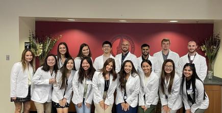 group of optometry school students posing in white coats