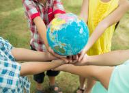 A group of young children standing in a circle holding a globe