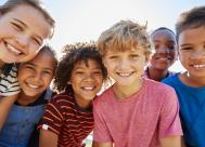 A happy group of elementary-school-aged children smiling and outside.