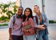 three smiling college students on the campus quad