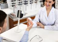 An optician handing a patient a contact lens case.