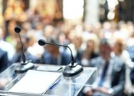 A full lecture hall with a closeup of a podium with microphones