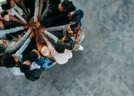a group of people in a circle holding their hands together to symbolize teamwork and support