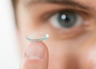 close-up of woman holding contact lens on her finger