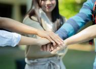 Group of young college students placing hands together